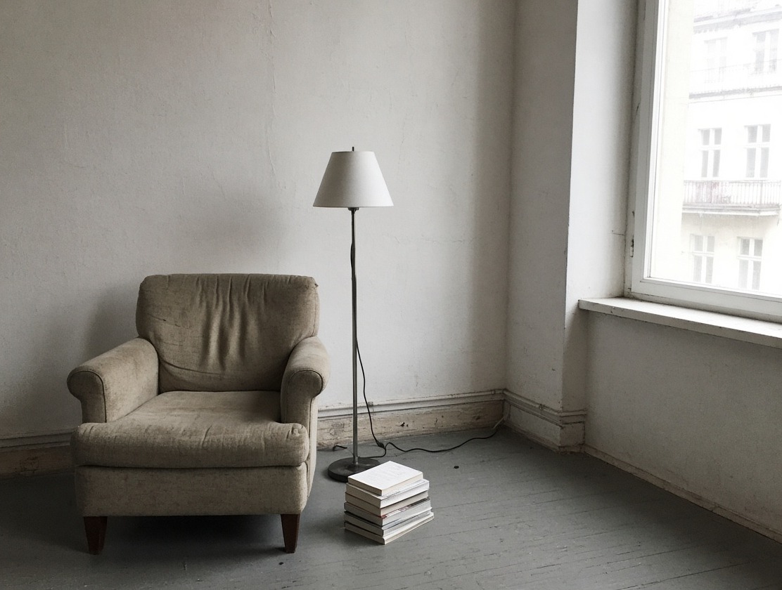 Beiger Sessel, schwarze Stehlampe mit Kabel auf dem Boden, Bücherstapel